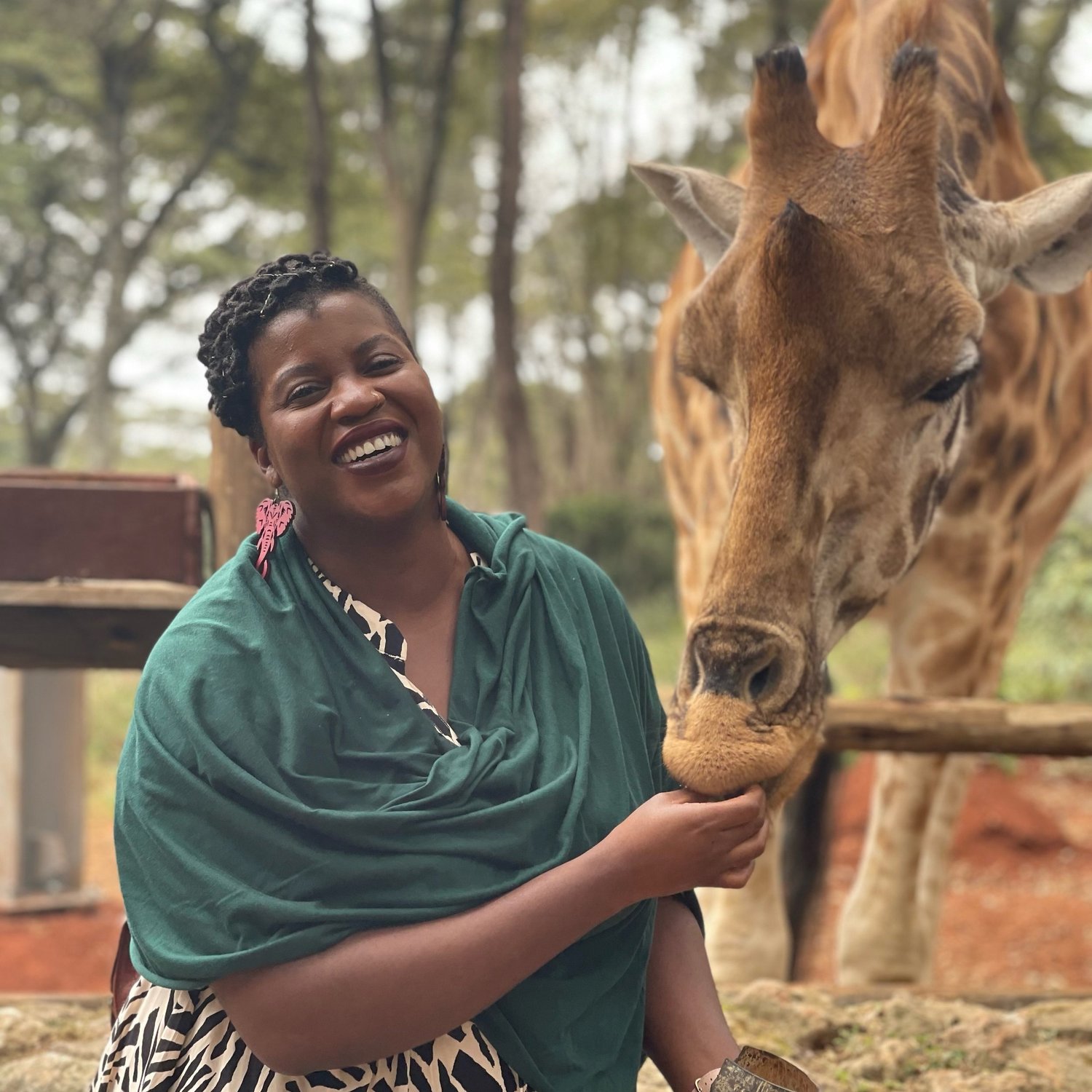 Ijeoma Duru smiles while feeding a giraffe
