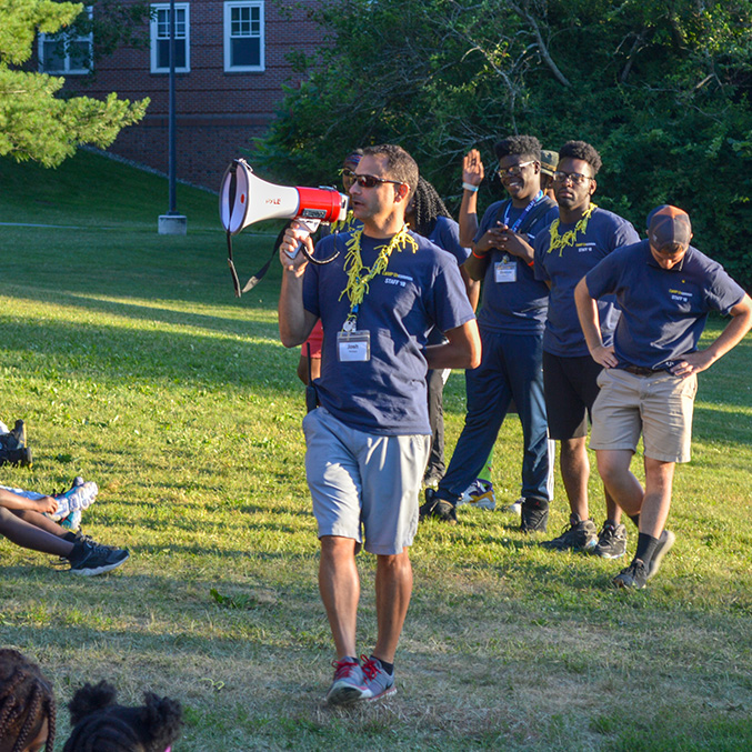 Josh Phillips uses a megaphone with campers who are gathered.