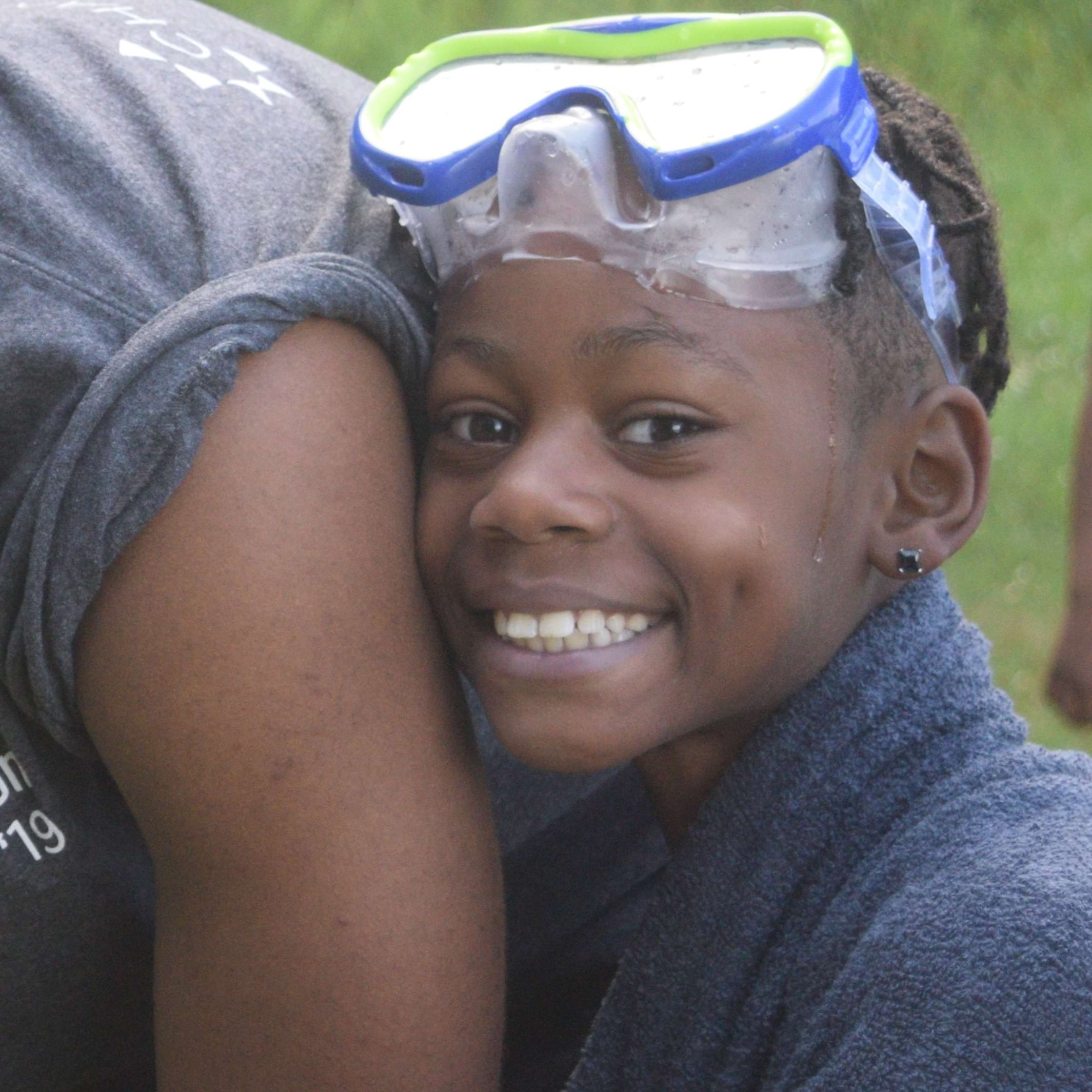 young boy wearing goggles smiles for the camera