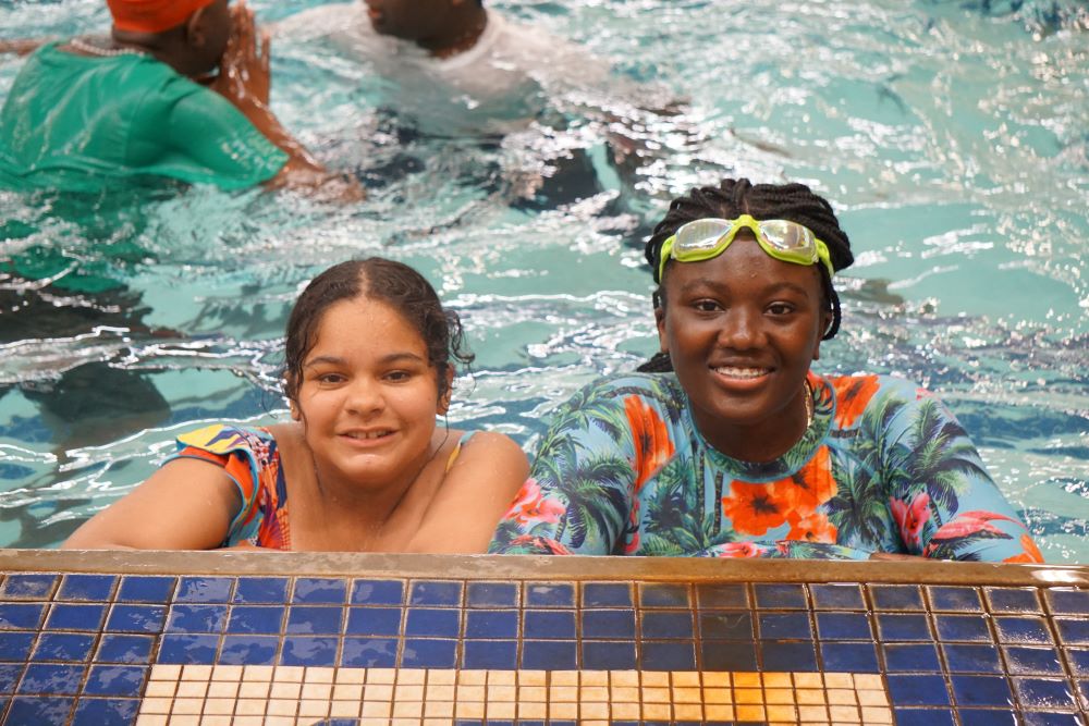 two girls smile while in a pool.